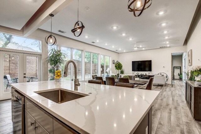 11300 Lake Dr, Austin, TX 78748 - kitchen with light wood-type flooring, a kitchen island with sink, light stone countertops, recessed lighting, and beam ceiling