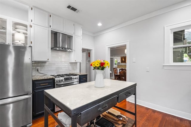 603 E Liberty Ave, Round Rock, TX 78664 - kitchen featuring freestanding refrigerator, wall chimney range hood, backsplash, white cabinetry, and dark wood-style floors