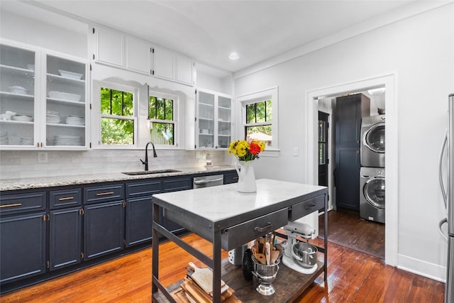 603 E Liberty Ave, Round Rock, TX 78664 - kitchen with stacked washer / dryer, dark wood finished floors, blue cabinets, tasteful backsplash, and stainless steel appliances