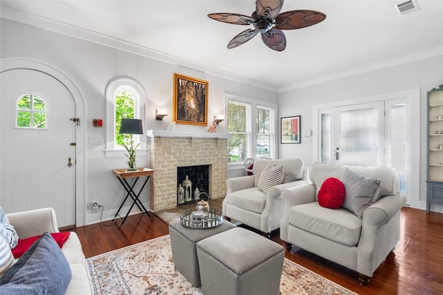 603 E Liberty Ave, Round Rock, TX 78664 - living room featuring a ceiling fan, wood finished floors, crown molding, and a brick fireplace