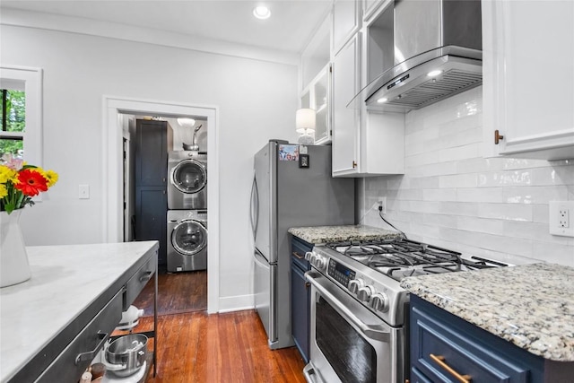 603 E Liberty Ave, Round Rock, TX 78664 - kitchen featuring gas stove, blue cabinets, wall chimney exhaust hood, stacked washer / drying machine, and white cabinets