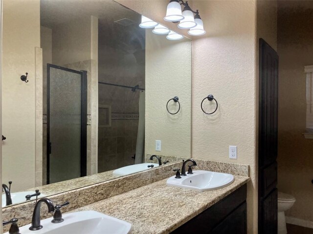 129 S Abrego Xing S, Floresville, TX 78114 - bathroom featuring a stall shower, a textured wall, and double vanity