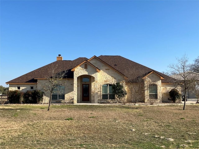 129 S Abrego Xing S, Floresville, TX 78114 - french country inspired facade with stone siding, a chimney, and a front lawn