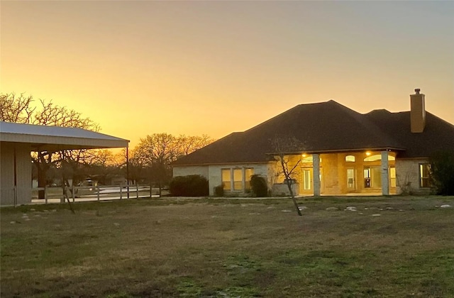 129 S Abrego Xing S, Floresville, TX 78114 - back of property at dusk featuring a chimney