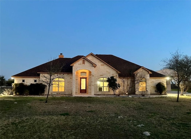 129 S Abrego Xing S, Floresville, TX 78114 - french country style house featuring stone siding, a chimney, and a front lawn