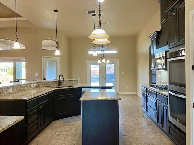 129 S Abrego Xing S, Floresville, TX 78114 - kitchen with a large island, appliances with stainless steel finishes, hanging light fixtures, light tile patterned floors, and a textured ceiling