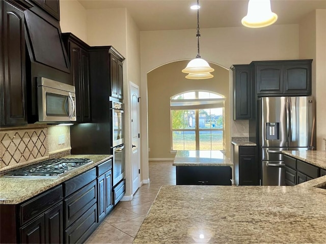 129 S Abrego Xing S, Floresville, TX 78114 - kitchen featuring stainless steel appliances, arched walkways, decorative backsplash, and light tile patterned floors