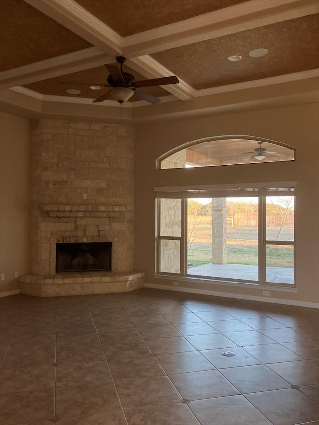 129 S Abrego Xing S, Floresville, TX 78114 - unfurnished living room with a ceiling fan, tile patterned flooring, coffered ceiling, beam ceiling, and a stone fireplace