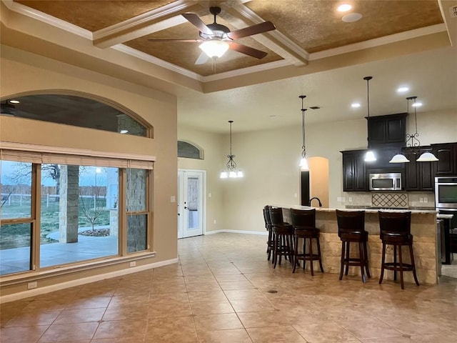 129 S Abrego Xing S, Floresville, TX 78114 - kitchen featuring stainless steel microwave, ceiling fan, decorative backsplash, a kitchen breakfast bar, and light countertops