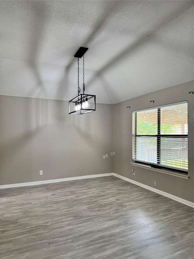 1000 Twin Creek Dr, Pflugerville, TX 78660 - empty room with vaulted ceiling, a textured ceiling, and wood finished floors