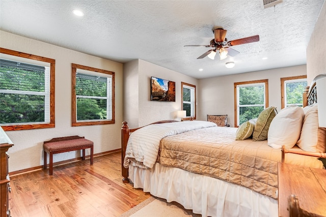 2308 Flite Acres Rd, Wimberley, TX 78676 - bedroom with light wood-type flooring, a textured ceiling, recessed lighting, a textured wall, and ceiling fan