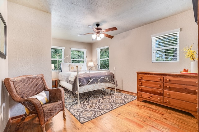 2308 Flite Acres Rd, Wimberley, TX 78676 - bedroom with a textured wall, wood finished floors, a textured ceiling, and ceiling fan
