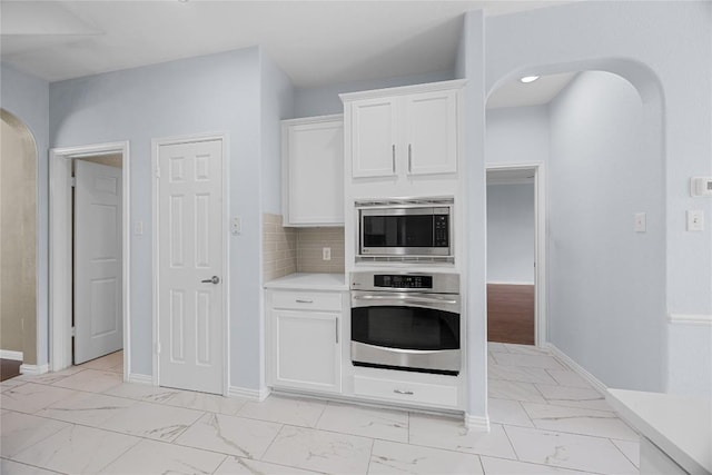 1601 Michael Robert Way, Cedar Park, TX 78613 - kitchen featuring appliances with stainless steel finishes, arched walkways, light marble finish flooring, light countertops, and white cabinets