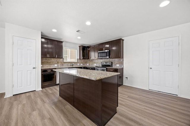 9207 Sandyford Ct, Killeen, TX 76542 - kitchen with appliances with stainless steel finishes, light wood-type flooring, dark brown cabinetry, decorative backsplash, and recessed lighting