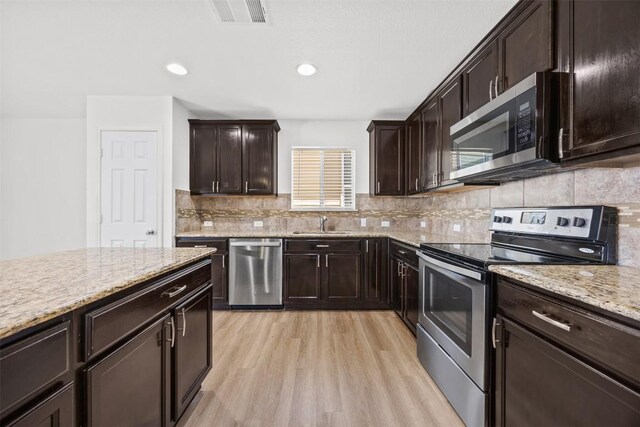 9207 Sandyford Ct, Killeen, TX 76542 - kitchen featuring appliances with stainless steel finishes, light wood finished floors, light stone counters, tasteful backsplash, and dark brown cabinetry