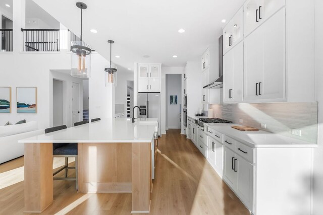 4612 Destination Way, Jonestown, TX 78645 - kitchen with appliances with stainless steel finishes, light wood finished floors, a kitchen breakfast bar, light countertops, and tasteful backsplash