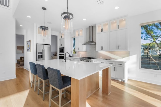4612 Destination Way, Jonestown, TX 78645 - kitchen with wall chimney exhaust hood, appliances with stainless steel finishes, tasteful backsplash, light wood-style floors, and recessed lighting