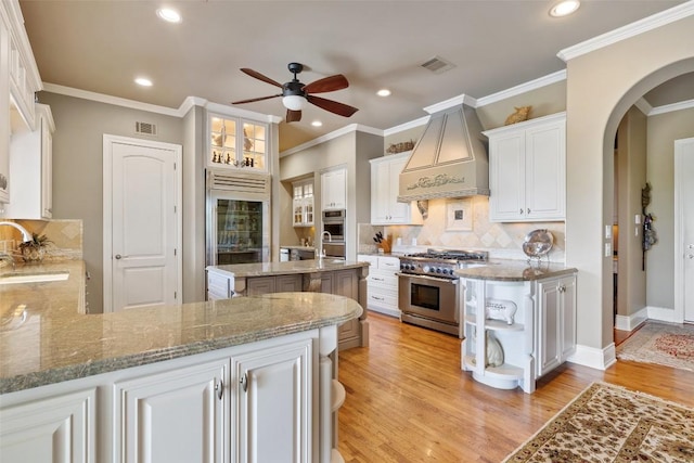 117 Bella Cima Dr, Austin, TX 78734 - kitchen featuring custom range hood, high quality appliances, ceiling fan, light wood-type flooring, and arched walkways