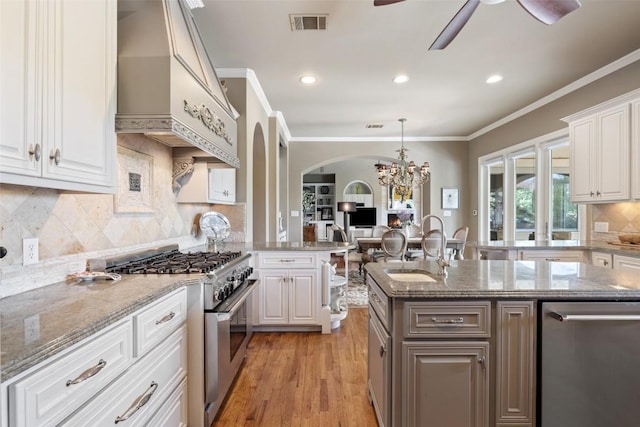 117 Bella Cima Dr, Austin, TX 78734 - kitchen featuring stainless steel appliances, premium range hood, ceiling fan, arched walkways, and white cabinetry