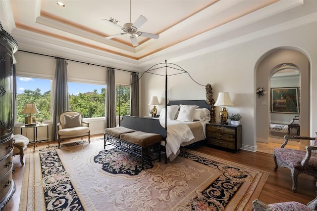 117 Bella Cima Dr, Austin, TX 78734 - bedroom featuring a tray ceiling, crown molding, arched walkways, wood finished floors, and a ceiling fan