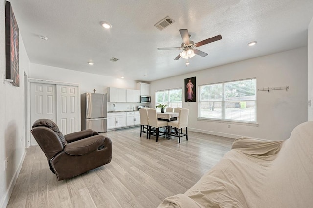 114 Crepe Myrtle Pkwy, Elgin, TX 78621 - living room with light wood-style floors, a ceiling fan, a textured ceiling, and recessed lighting