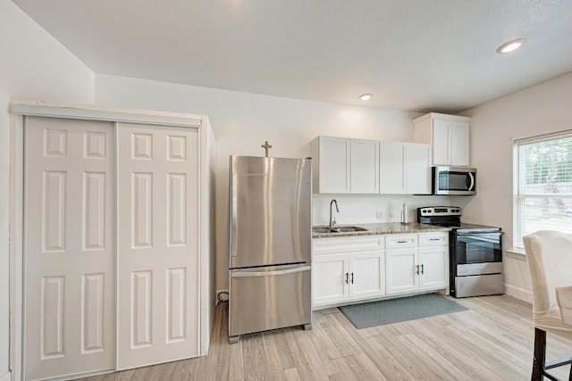 114 Crepe Myrtle Pkwy, Elgin, TX 78621 - kitchen with stainless steel appliances, white cabinets, light stone counters, light wood finished floors, and recessed lighting