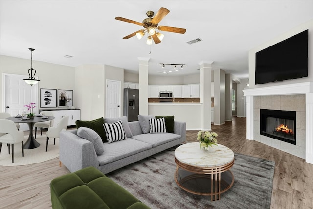 1612 Cora Marie Dr, Pflugerville, TX 78660 - living room with ceiling fan, light wood finished floors, a fireplace, rail lighting, and ornate columns