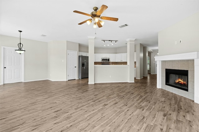 1612 Cora Marie Dr, Pflugerville, TX 78660 - unfurnished living room featuring a ceiling fan, light wood finished floors, a fireplace, and rail lighting