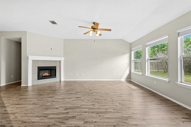 1612 Cora Marie Dr, Pflugerville, TX 78660 - unfurnished living room featuring a ceiling fan, healthy amount of natural light, wood finished floors, vaulted ceiling, and a tiled fireplace
