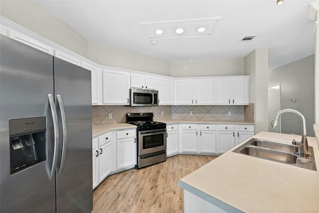 1612 Cora Marie Dr, Pflugerville, TX 78660 - kitchen with stainless steel appliances, light wood-style floors, white cabinets, tasteful backsplash, and light countertops