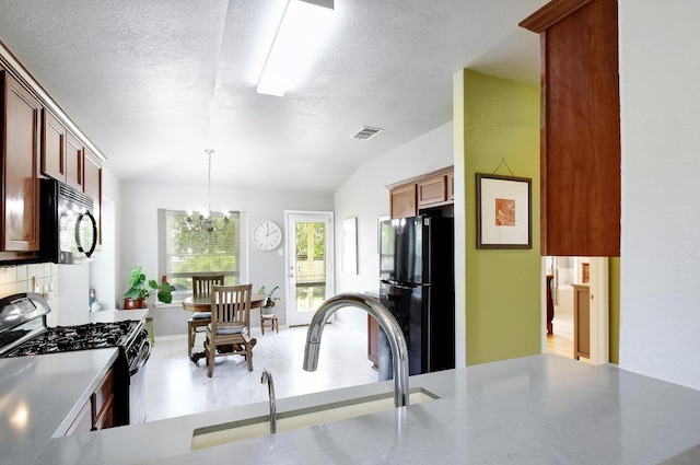 106 Wild Plum, San Marcos, TX 78666 - kitchen with black appliances, a chandelier, pendant lighting, a textured ceiling, and decorative backsplash