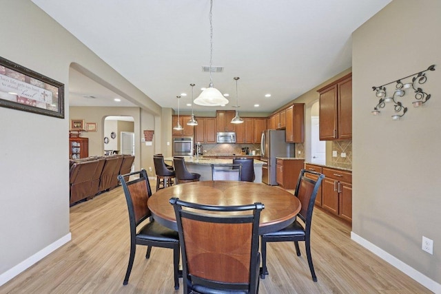 1124 Calla Lily Blvd, Leander, TX 78641 - dining space featuring light wood-style flooring, arched walkways, and recessed lighting