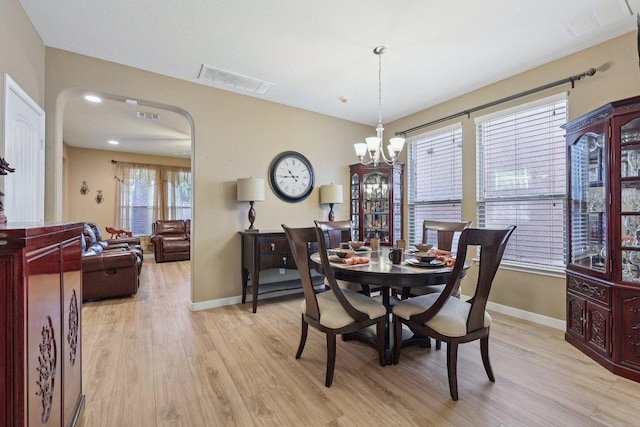 1124 Calla Lily Blvd, Leander, TX 78641 - dining room with light wood finished floors, arched walkways, and a chandelier