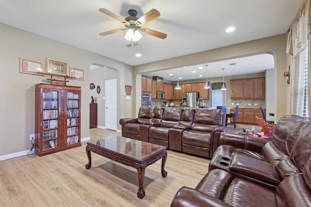 1124 Calla Lily Blvd, Leander, TX 78641 - living room with arched walkways, light wood-style flooring, a ceiling fan, and recessed lighting