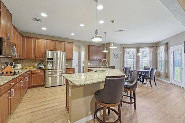 1124 Calla Lily Blvd, Leander, TX 78641 - kitchen with appliances with stainless steel finishes, light wood-style flooring, a center island with sink, backsplash, and recessed lighting