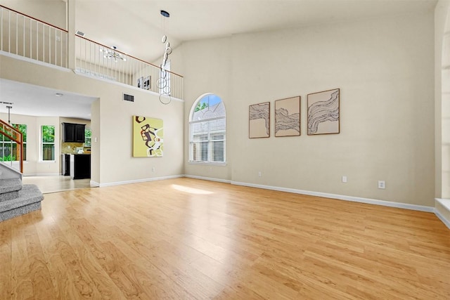 3528 Ruby Red Dr, Austin, TX 78728 - unfurnished living room featuring light wood-type flooring, stairway, and a towering ceiling