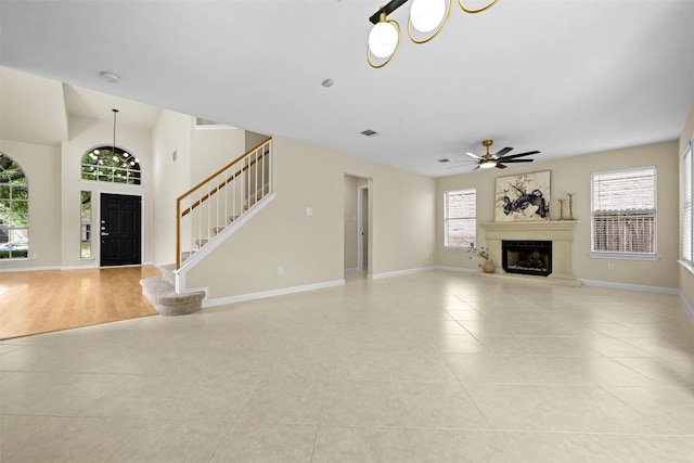 3528 Ruby Red Dr, Austin, TX 78728 - unfurnished living room with light tile patterned floors, a fireplace with raised hearth, a ceiling fan, and stairway