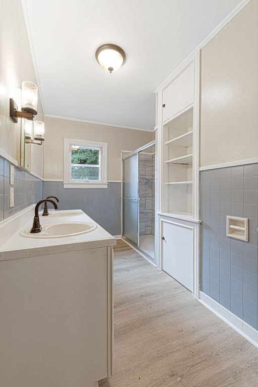 1414 E 4th St, Lampasas, TX 76550 - full bath featuring wood finished floors, ornamental molding, tile walls, vanity, and a shower stall