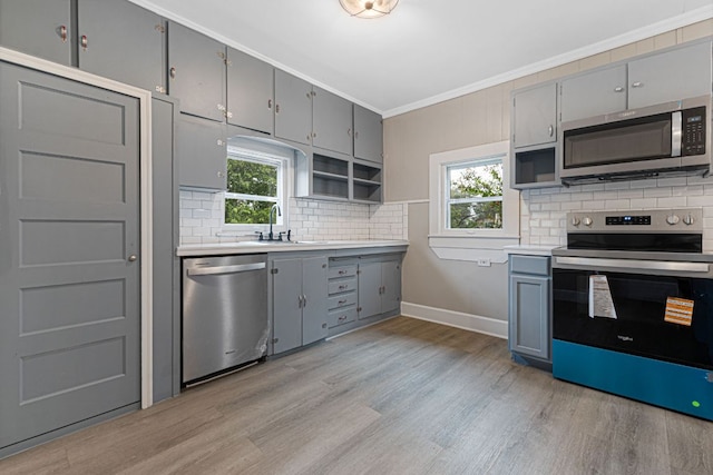 1414 E 4th St, Lampasas, TX 76550 - kitchen featuring appliances with stainless steel finishes, gray cabinets, light wood-style flooring, open shelves, and crown molding