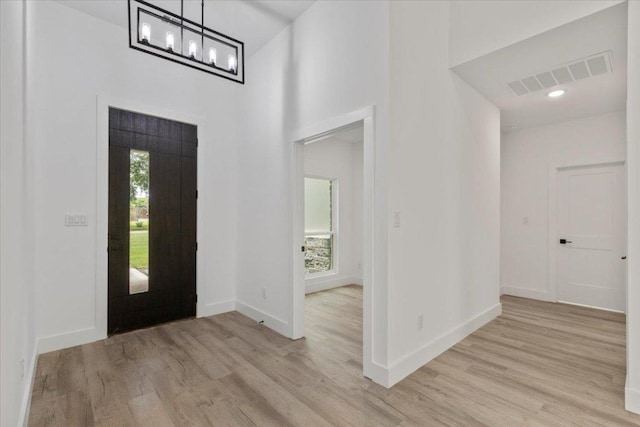 108 Bill St, Elgin, TX 78621 - entrance foyer with light wood-style flooring, a high ceiling, and a chandelier