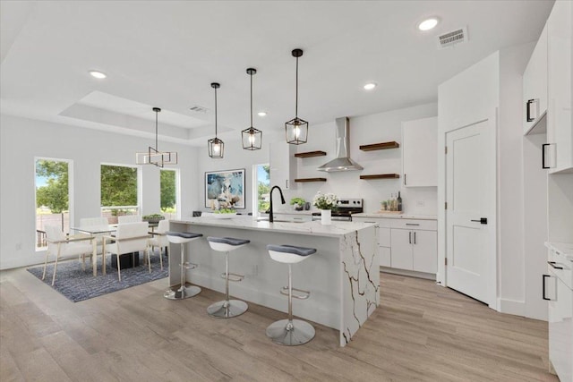 108 Bill St, Elgin, TX 78621 - kitchen featuring wall chimney range hood, stainless steel range with electric stovetop, light wood-style floors, open shelves, and recessed lighting