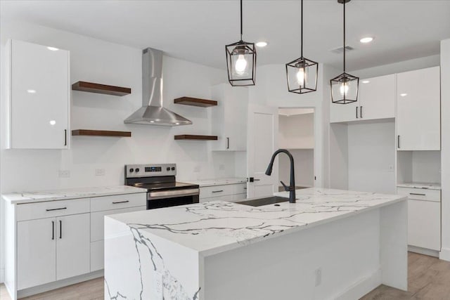 108 Bill St, Elgin, TX 78621 - kitchen with open shelves, stainless steel electric stove, wall chimney range hood, white cabinetry, and a center island with sink