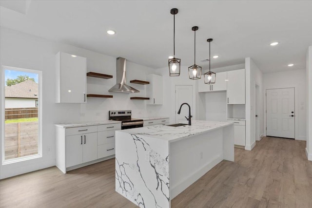 108 Bill St, Elgin, TX 78621 - kitchen featuring stainless steel range with electric cooktop, open shelves, white cabinets, light wood finished floors, and wall chimney exhaust hood