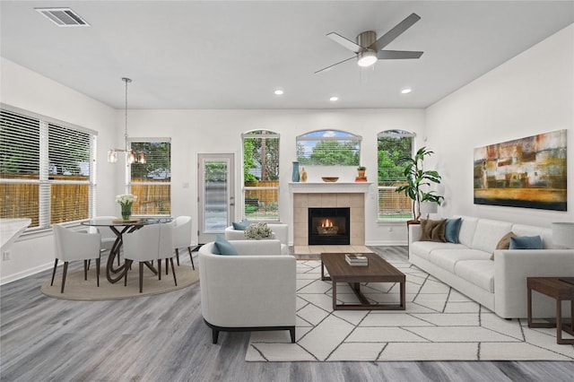 8721 Little Laura Dr, Austin, TX 78757 - living room featuring wood finished floors, ceiling fan, a tiled fireplace, recessed lighting, and a chandelier