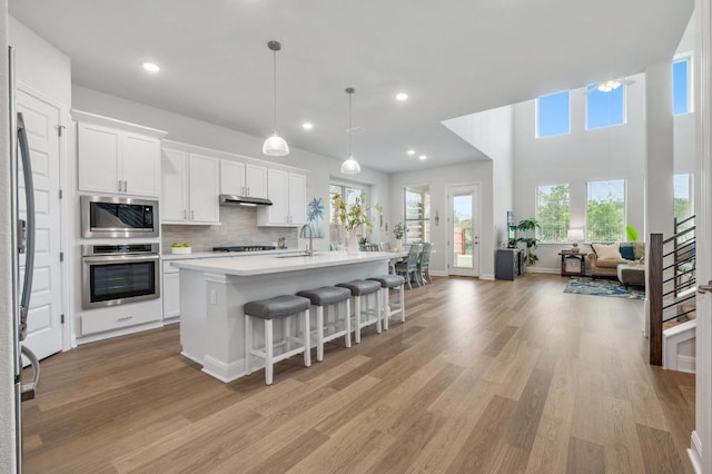 913 Landing Ln, Leander, TX 78641 - kitchen with appliances with stainless steel finishes, a breakfast bar, white cabinets, light countertops, and open floor plan
