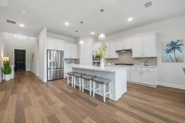 913 Landing Ln, Leander, TX 78641 - kitchen with stainless steel fridge with ice dispenser, gas cooktop, under cabinet range hood, decorative backsplash, and recessed lighting