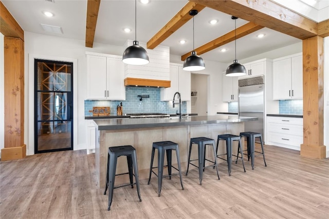 4100 Peak Look Out Dr, Austin, TX 78738 - kitchen with built in refrigerator, dark countertops, light wood finished floors, beamed ceiling, and tasteful backsplash