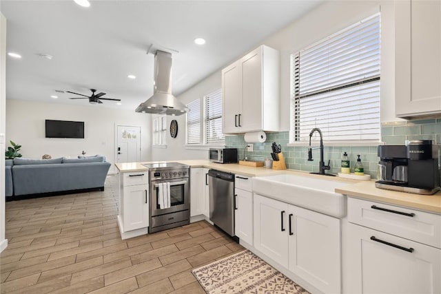 4100 Peak Look Out Dr, Austin, TX 78738 - kitchen featuring stainless steel appliances, island exhaust hood, white cabinets, ceiling fan, and recessed lighting