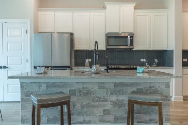 103 Periwinkle Ln, Bastrop, TX 78602 - kitchen with stainless steel appliances, backsplash, a breakfast bar area, and an island with sink