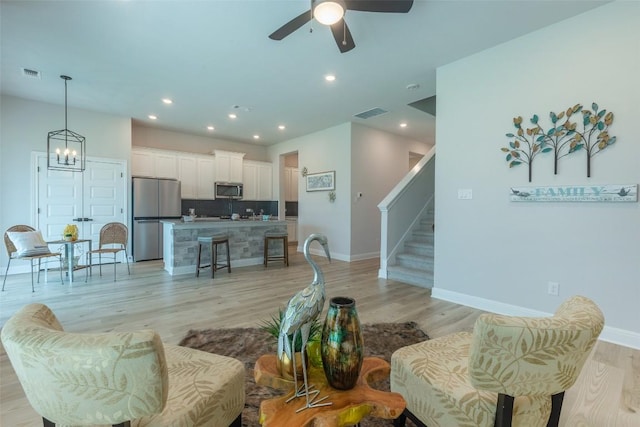 103 Periwinkle Ln, Bastrop, TX 78602 - living area with stairway, light wood-style flooring, a ceiling fan, a chandelier, and recessed lighting